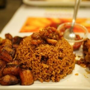 A tempting plate of Jollof rice accompanied by savory fried plantains. Perfect meal idea.